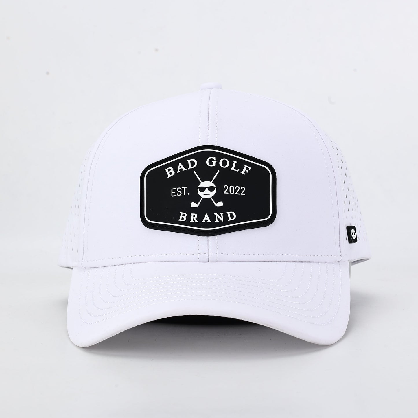 White cap with a black logo on a light gray background. The summit collection by Bad Golf Brand.