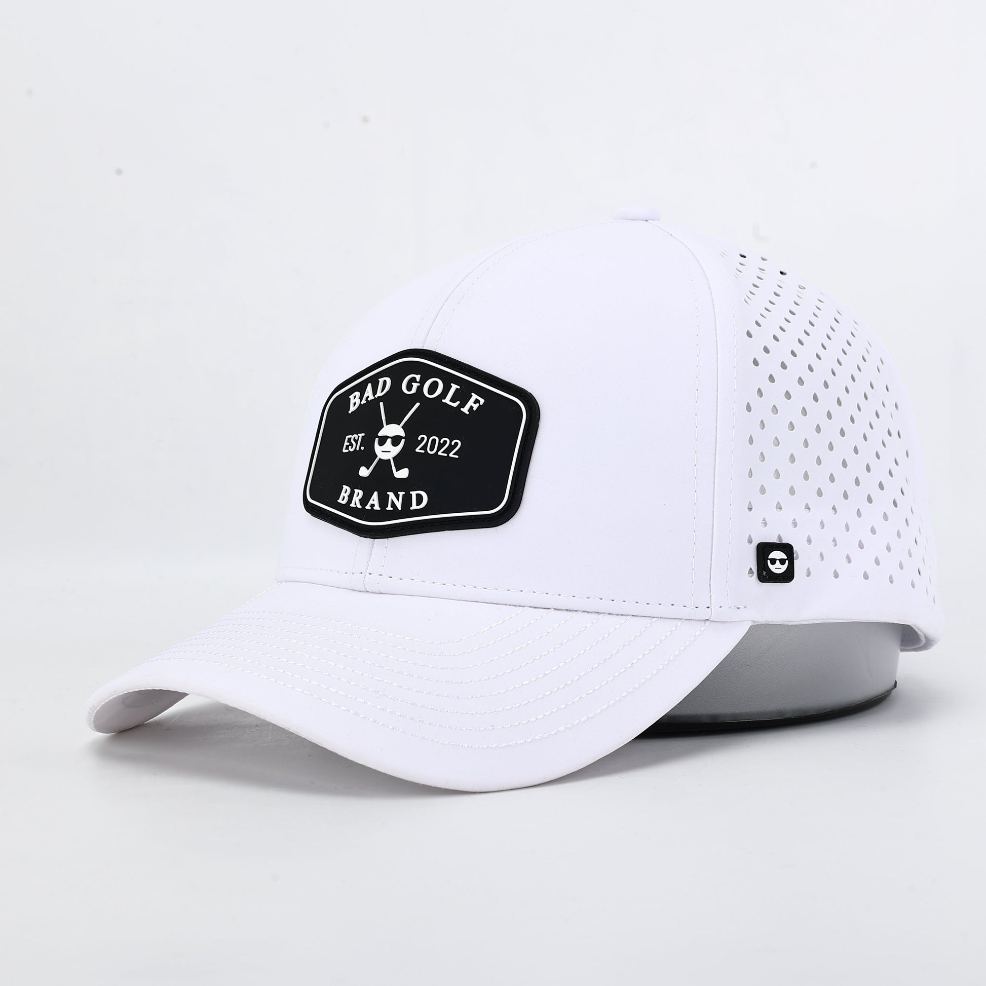White cap with a black logo on a light gray background The summit collection by Bad Golf Brand.